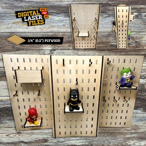 Puede incluir: Un expositor de pared de tres secciones con tablero de clavijas hecho de madera contrachapada de 6,35 mm con estantes y ganchos para exhibir figuras de acción. El tablero de clavijas está hecho de madera y tiene un acabado natural. Los estantes están hechos de madera y tienen un acabado natural. Los ganchos están hechos de metal y tienen un acabado negro. Las figuras de acción están hechas de plástico y tienen una variedad de colores. El tablero de clavijas es una excelente manera de exhibir tus figuras de acción y otros objetos de colección favoritos.