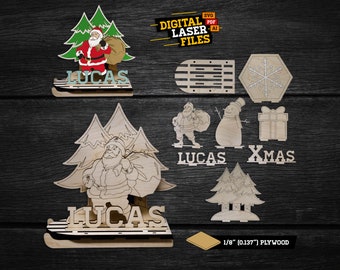 May include: Digital laser cut files for a Christmas decoration featuring Santa Claus with a bag of gifts, two Christmas trees, and the name "Lucas". The design also includes a snowman, a gift box, and the word "Xmas". The files are for 1/8 inch plywood.