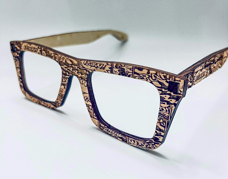 Puede incluir: Un par de gafas de madera marr&oacute;n con un patr&oacute;n de c&oacute;mic. Las gafas tienen una forma cuadrada y lentes transparentes.