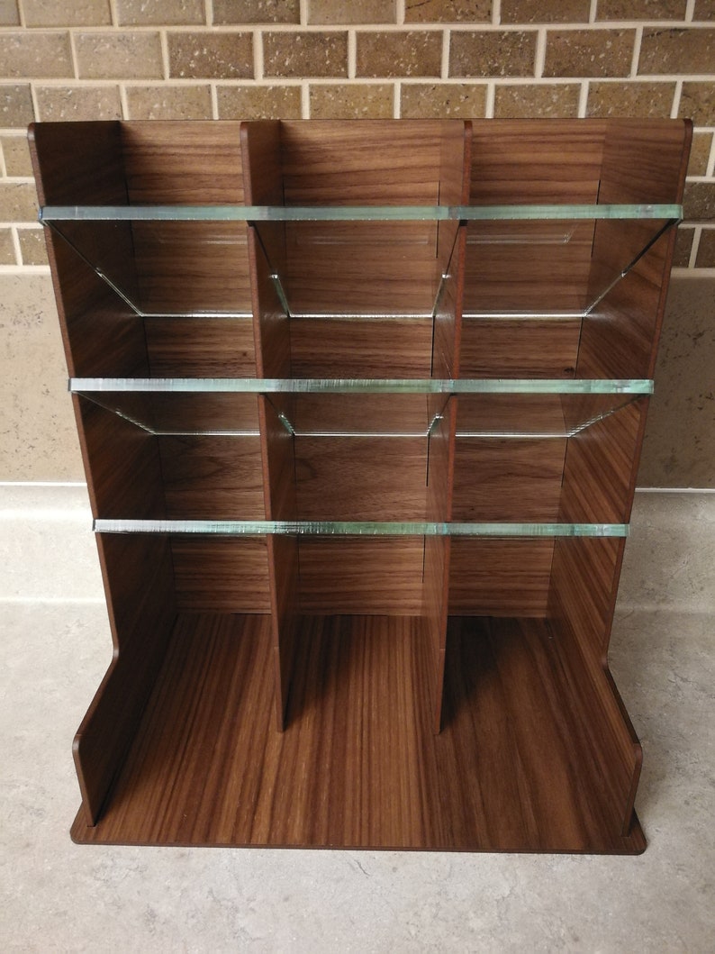 Puede incluir: Un organizador de madera con m&uacute;ltiples compartimentos y estantes de vidrio. El organizador est&aacute; hecho de madera oscura con un patr&oacute;n de veta natural.