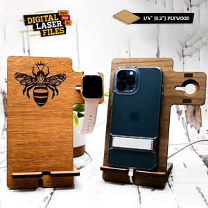 May include: Wooden phone and watch stand with a bee design. The stand is made of 1/4 inch plywood and has a slot for a phone and a watch. The stand is brown and has a natural wood finish.