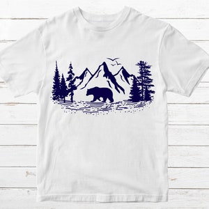 May include: White t-shirt with a navy blue silhouette of a bear walking in front of mountains and trees.