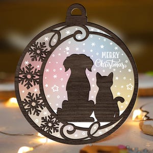 May include: A wooden Christmas ornament featuring a dog and cat silhouette inside a circular frame. The frame has snowflake cutouts and the words "Merry Christmas". The background is a pastel gradient of pink, blue, and yellow.