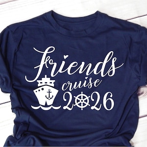 May include: Navy blue t-shirt with white text and graphics. The shirt features the words "Friends cruise 2026" in a script font, along with a cruise ship and a ship's wheel graphic. The shirt is made of a soft material.