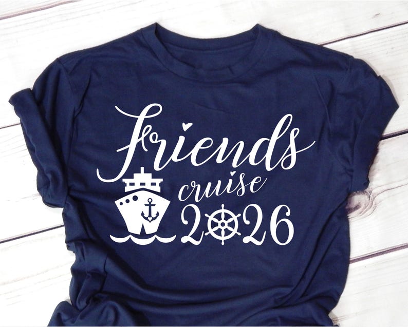 May include: Navy blue t-shirt with white text and graphics. The shirt features the words "Friends cruise 2026" in a script font, along with a cruise ship and a ship's wheel graphic. The shirt is made of a soft material.
