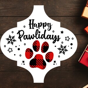May include: White sign with a red and black paw print in the center. The sign says "Happy Pawlidays" in black cursive lettering.