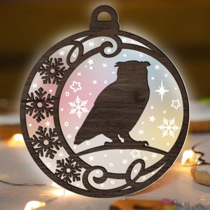 May include: A wooden Christmas ornament shaped like a circle with a detailed design of snowflakes and an owl. The ornament is painted in shades of brown and white.