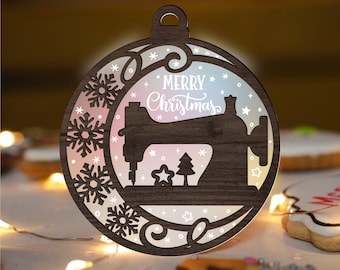May include: A wooden Christmas bauble shaped like a sewing machine with a white "Merry Christmas" inscription. The bauble has a gradient background with snowflakes and stars.