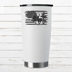 K&ouml;nnte beinhalten: Ein wei&szlig;er Edelstahlbecher mit einem schwarz-wei&szlig;en Design eines Hirsches, der vor einer abgenutzten amerikanischen Flagge mit B&auml;umen und einem Vollmond steht.