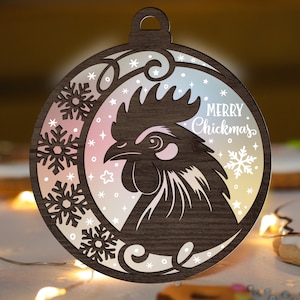 Może przedstawiać: Drewniana ozdoba choinkowa w kształcie koła z wzorem koguta i tekstem "Merry Chickmas". Ozdoba ma gradient kolorów różowego, niebieskiego i białego.