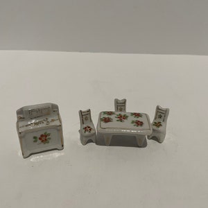 May include: A miniature porcelain dining set with a table and four chairs. The set is decorated with a floral pattern in red, green, and gold.