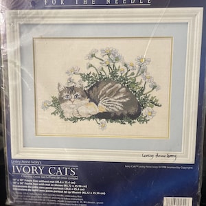 May include: A cross-stitch kit featuring a detailed image of a cat nestled among daisies. The kit is titled "IVORY CATS" and includes frame size measurements of 14" x 10" and 18" x 14". The design is by Lesley Anne Ivory.
