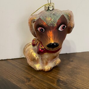 Handgeblasenes, handbemaltes Hundeornament aus Glas, mit Glitzer überzogen und mit einer roten Schleife gebunden