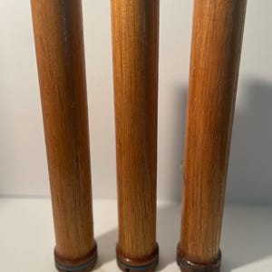 May include: Three wooden dowels with a blue and white band around the bottom. The dowels are brown and have a natural wood grain.