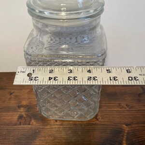 Op de afbeelding: Een glazen pot met een diamantpatroon en een deksel. De pot is ongeveer 15 cm hoog.