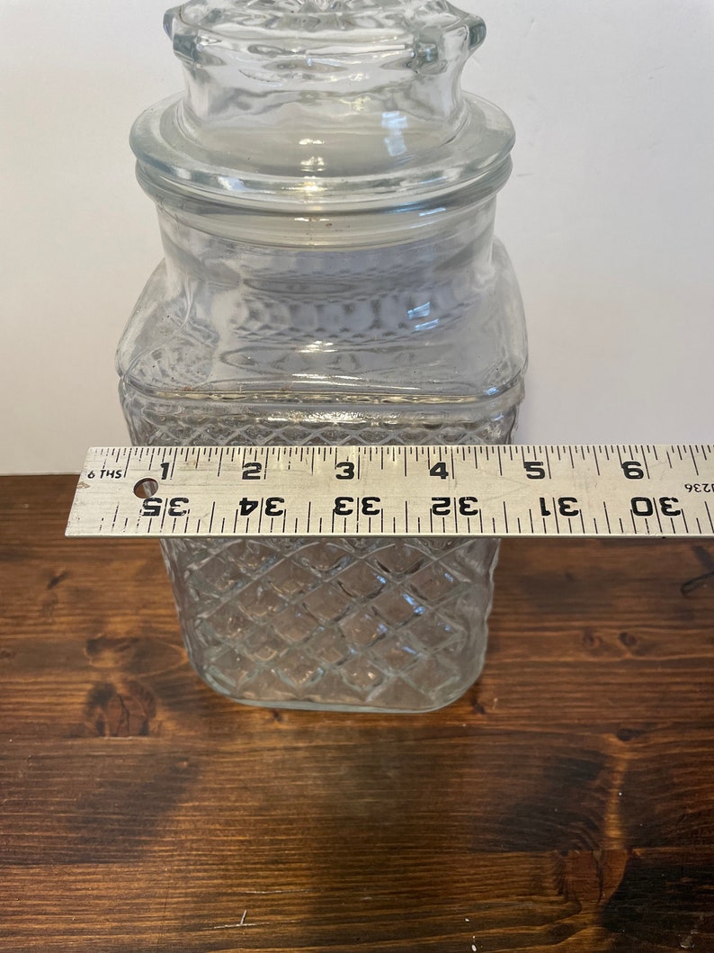 Op de afbeelding: Een glazen pot met een diamantpatroon en een deksel. De pot is ongeveer 15 cm hoog.