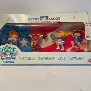 May include: A set of four Cabbage Patch Kids Olympikids figurines, each representing a different sport: track and field, weightlifting, tennis, and gymnastics. The figurines are dressed in red, white, and blue, and each holds a prop related to their sport. The packaging features the 1994 US Olympic Team logo and the words "Official Mascot".