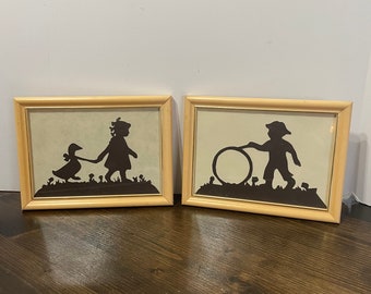 Par de siluetas enmarcadas estilo vintage Scherenschnitte, arte popular infantil y para guardería: niña con pato, niño con aro, dulce decoración retro.