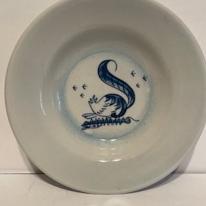 May include: A white ceramic bowl with a blue and white design of a squirrel with a curly tail. The squirrel is surrounded by small blue arrows.