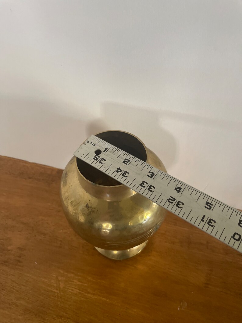 May include: A gold metal vase with a round body and a flared base. The vase is approximately 3.5 inches tall.