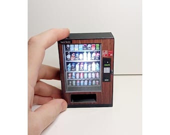 Könnte beinhalten: Ein Miniatur-Automat mit Holzmaserung. Der Automat hat eine transparente Frontplatte mit einer Vielzahl von bunten Getränken, die im Inneren sichtbar sind. Der Automat hat einen schwarzen Rahmen und ein rotes Etikett mit der Aufschrift "Snack Master".