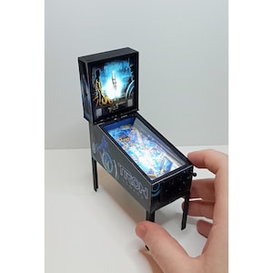 Może przedstawiać: Biały ceramiczny kubek z czarnym uchwytem i napisem "But First, Coffee" w stylu odręcznym. Kubek stoi na białej powierzchni. Kubek ma około 10 cm wysokości.