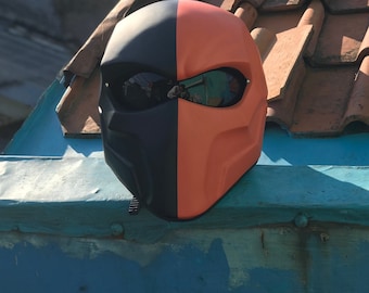 Puede incluir: Un casco de moto negro y naranja con un diseño de media cara y una visera. El casco tiene una forma afilada y angular y un esquema de color audaz.