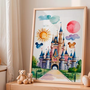 Pode incluir: Impressão em aquarela de um castelo de conto de fadas em rosa e azul, emoldurada em madeira clara. A obra de arte inclui um sol, nuvens e silhuetas do Mickey Mouse. A impressão é exibida em uma mesa de madeira com ursinhos de pelúcia.