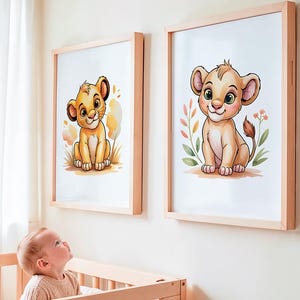 May include: Two framed art prints featuring watercolor illustrations of a cartoon lion cub. The lion cubs are sitting, with big eyes and a friendly expression. The prints are in light wood frames, suitable for a nursery or children's room.