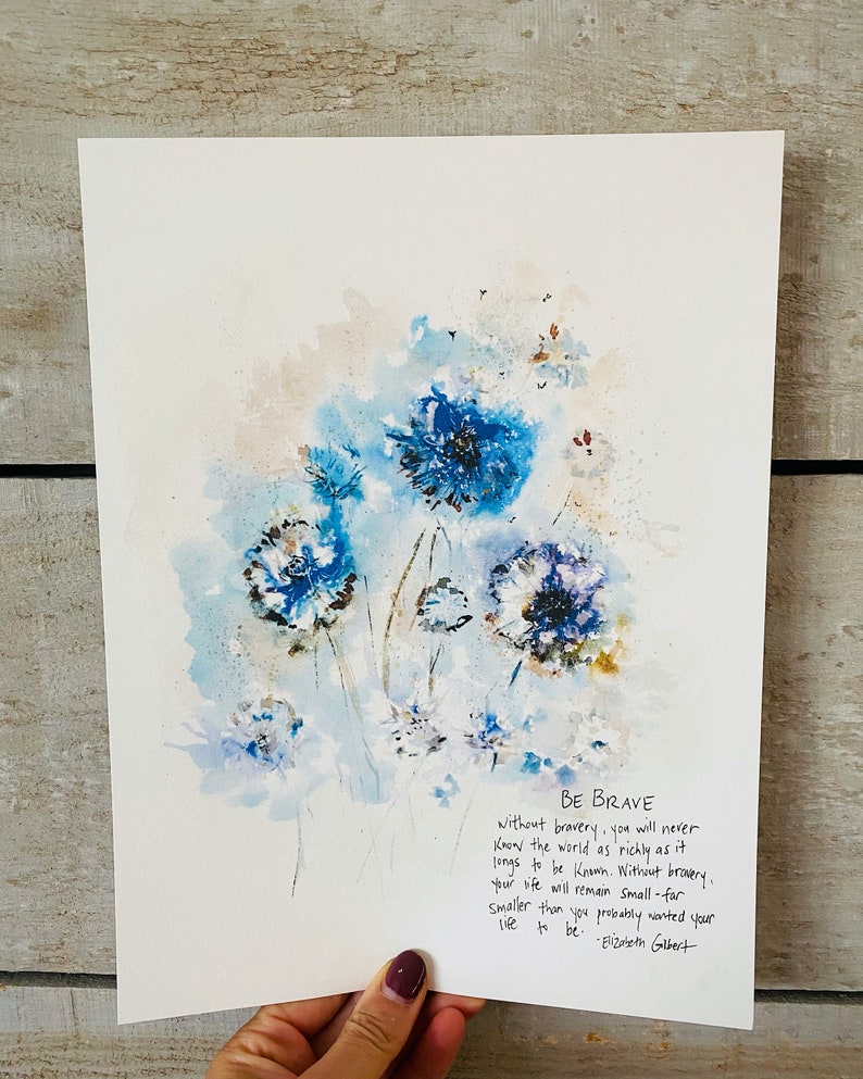 May include: A watercolor painting of blue flowers with a quote by Elizabeth Gilbert that reads "Be Brave. Without bravery, you will never know the world as richly as it longs to be known. Without bravery, your life will remain small - far smaller than you probably wanted your life to be."