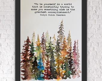 Op de afbeelding: Een ingelijste kunstdruk met een aquarel schilderij van een bos in tinten bruin, groen en blauw. Het kunstwerk bevat het citaat: "Wees jezelf in een wereld die constant probeert je iets anders te maken, is de grootste prestatie." van Ralph Waldo Emerson.