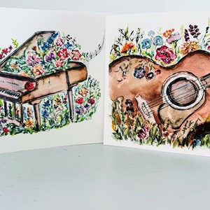 Peut inclure: Deux aquarelles sur papier blanc. La premi&egrave;re peinture repr&eacute;sente un piano &agrave; queue brun avec un arrangement floral sur le dessus. La deuxi&egrave;me peinture repr&eacute;sente une guitare acoustique brune avec un arrangement floral autour.