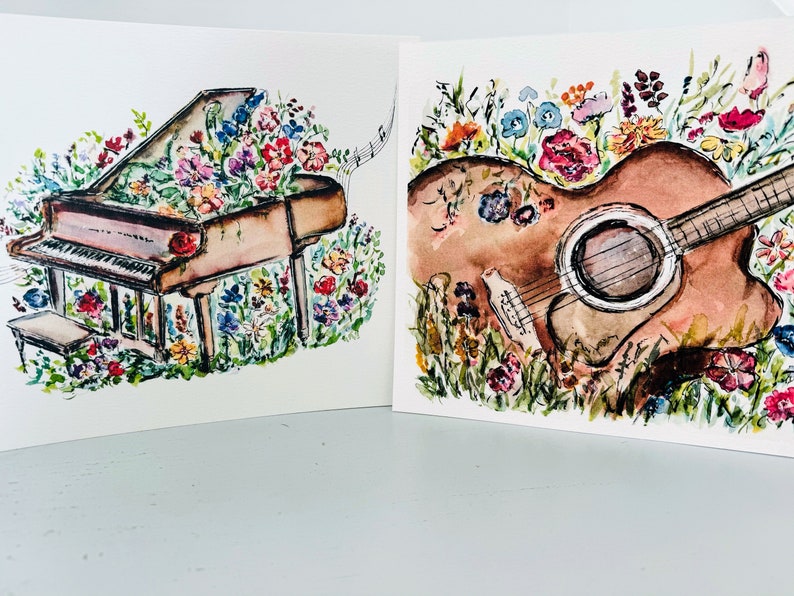 Peut inclure: Deux aquarelles sur papier blanc. La premi&egrave;re peinture repr&eacute;sente un piano &agrave; queue brun avec un arrangement floral sur le dessus. La deuxi&egrave;me peinture repr&eacute;sente une guitare acoustique brune avec un arrangement floral autour.