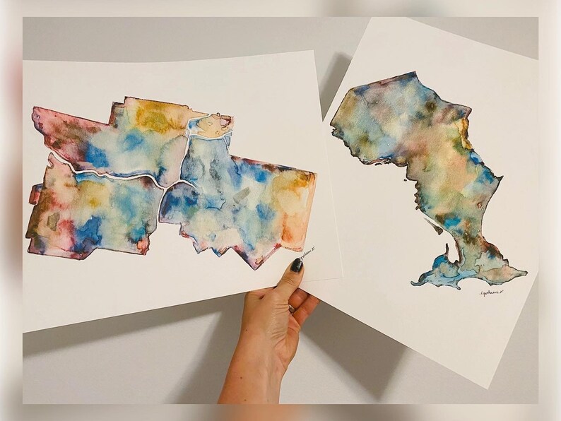 K&ouml;nnte beinhalten: Zwei Aquarellbilder von Karten. Die erste Karte zeigt eine Stadt mit mehreren Stadtteilen, die in Blaut&ouml;nen, Rosa, Gelb und Braun gemalt sind. Die zweite Karte zeigt einen Bundesstaat oder eine Region, die in Blaut&ouml;nen, Gr&uuml;n und Braun gemalt ist. Beide Karten sind auf wei&szlig;em Papier.