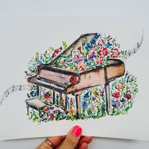 Peut inclure: Une peinture &agrave; l'aquarelle d'un piano &agrave; queue avec des fleurs qui poussent dessus. Le piano est brun et blanc, et les fleurs sont de diff&eacute;rentes couleurs, notamment rose, rouge, jaune et bleu. La peinture est sur un fond blanc.