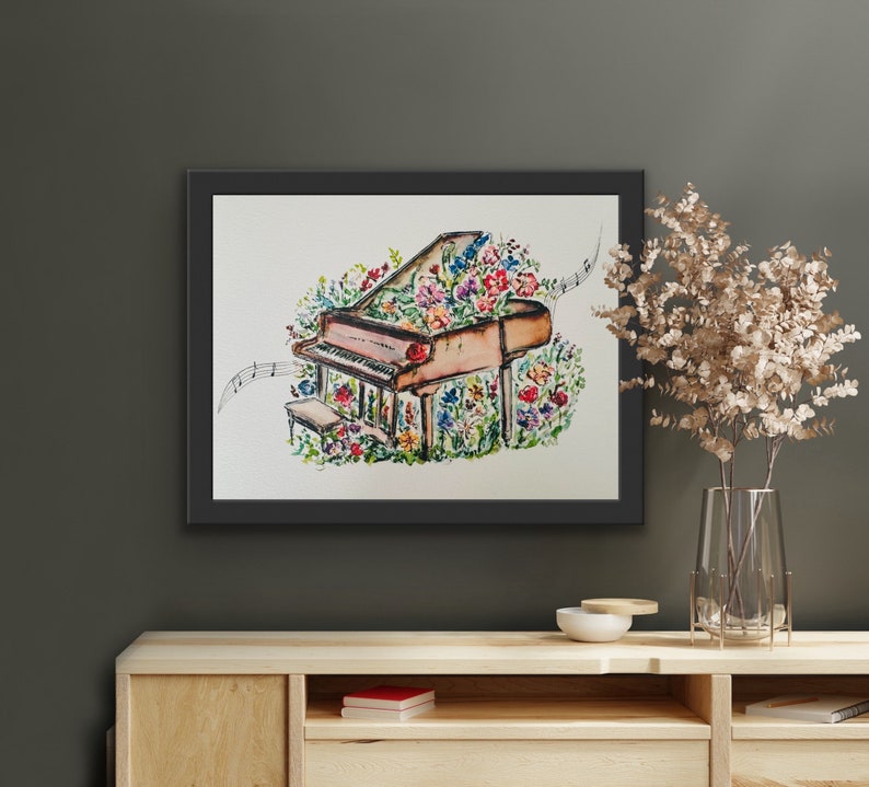 Peut inclure: Une peinture &agrave; l'aquarelle d'un piano &agrave; queue avec des fleurs qui poussent dessus. Le piano est brun et les fleurs sont roses, violettes et jaunes. La peinture est encadr&eacute;e en noir.