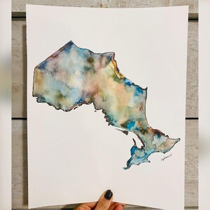 Pu&ograve; includere: Dipinto ad acquerello del contorno della provincia dell'Ontario, Canada. Il dipinto &egrave; realizzato in tonalit&agrave; di blu, verde e marrone.