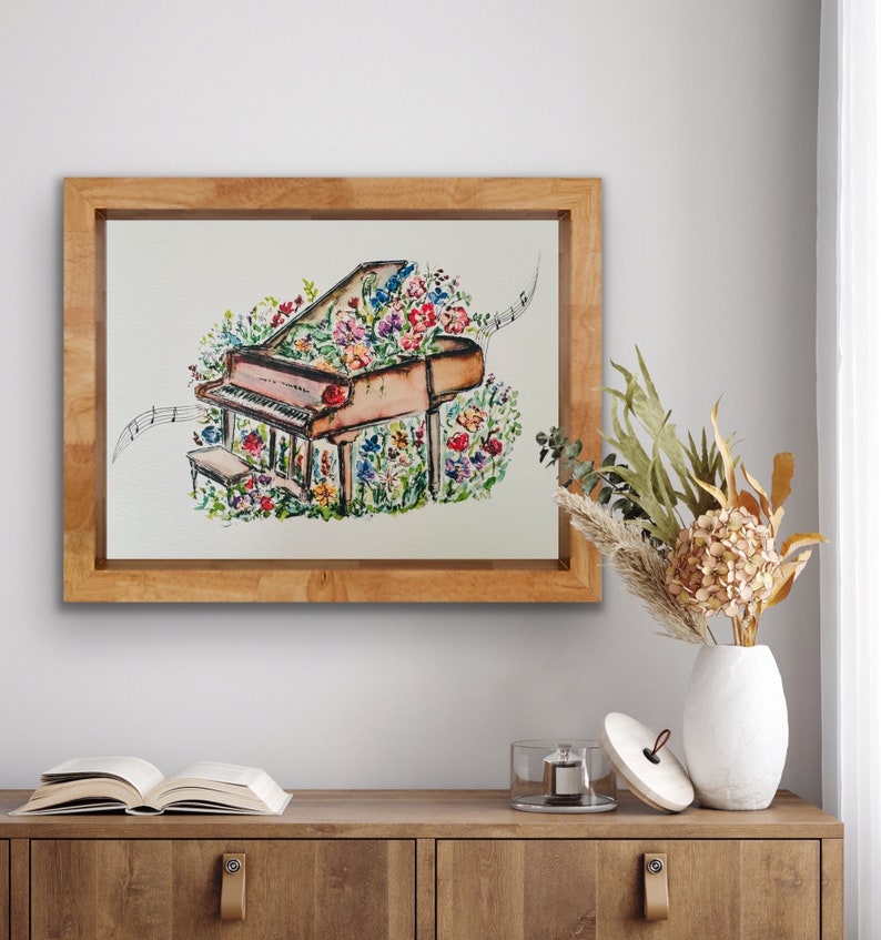 Peut inclure: Une peinture &agrave; l'aquarelle d'un piano &agrave; queue avec des fleurs qui poussent dessus. Le piano est brun et les fleurs sont color&eacute;es. La peinture est encadr&eacute;e dans un cadre en bois.