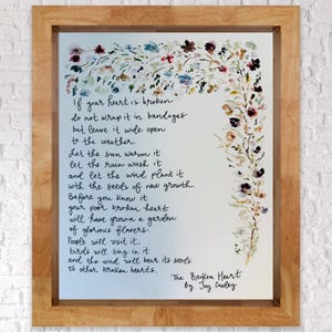 May include: A watercolour painting of a floral border with a poem about healing a broken heart. The poem reads: "If your heart is broken, do not wrap it in bandages but leave it wide open to the weather. Let the sun warm it, let the rain wash it, and let the wind plant it with the seeds of new growth. Before you know it, your poor broken heart will have grown a garden of glorious flowers. People will visit it, birds will sing in it, and the wind will bear its seeds to other broken hearts." The poem is signed "The Broken Heart by Joy Cowley."