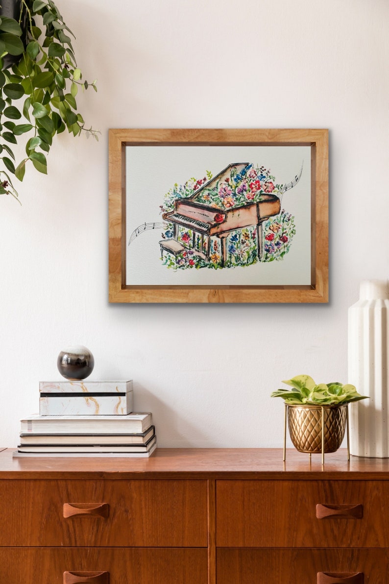Peut inclure: Une peinture &agrave; l'aquarelle encadr&eacute;e d'un piano &agrave; queue recouvert de fleurs color&eacute;es. Le piano est entour&eacute; de notes de musique et a un petit tabouret. La peinture est sur un fond blanc.