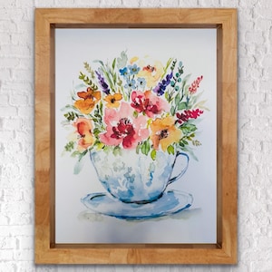 Peut inclure: Peinture à l'aquarelle d'une tasse à thé débordant de fleurs colorées. La tasse et la soucoupe sont bleu clair avec un motif floral. Les fleurs sont un mélange de rose, d'orange, de jaune et de violet, encadrées de bois.