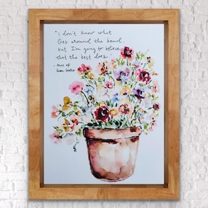 Może przedstawiać: Oprawiony wydruk akwarelowy przedstawiający kompozycję kwiatową w terakotowej doniczce. Kwiaty to mieszanka różu, fioletu, żółci i czerwieni. Wydruk zawiera cytat z "Ani z Zielonego Wzgórza" czarnym pismem.