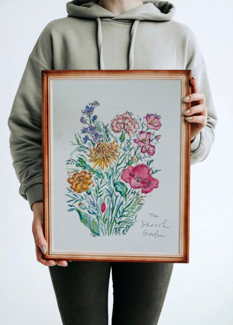 May include: A framed watercolor painting of a bouquet of flowers in shades of pink, yellow, and red. The flowers are arranged in a vase and the painting is signed "The Sketch Garden".