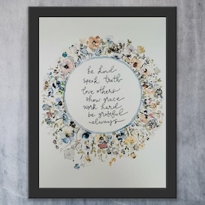 Peut inclure: Une impression encadrée à l'aquarelle avec une couronne florale entourant un cercle central contenant du texte manuscrit. Le texte dit : « be kind, speak truth, love others, show grace, work hard, be grateful, always ». Les fleurs sont bleues, roses et pêche.