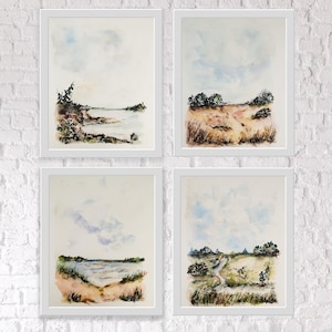 Peut inclure: Quatre aquarelles encadrées représentant différents paysages. Chaque peinture présente un ciel avec des nuages, un champ herbeux et un chemin ou une étendue d'eau. Les peintures sont dans des cadres blancs et sont disposées en grille.