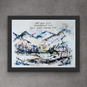 May include: Watercolour painting of a mountainous landscape with a lake in the foreground. The mountains are painted in shades of blue, purple and grey, with hints of green and brown. The lake is a light blue colour, and there are trees and bushes along the shore. The painting is framed in a black frame.