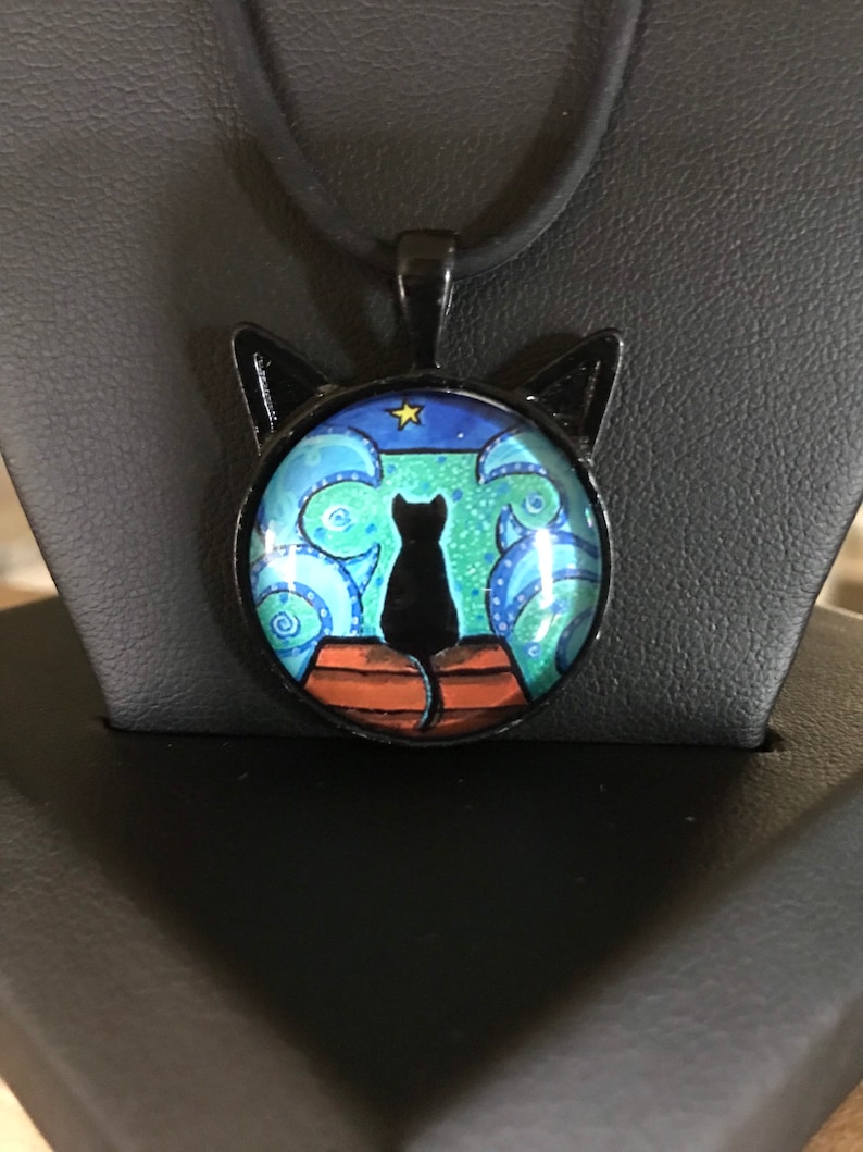 swirly ocean cat pendant on an 18\u201d black necklace Cat on a dock