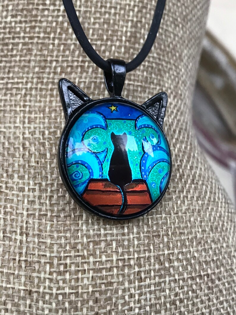 swirly ocean cat pendant on an 18\u201d black necklace Cat on a dock