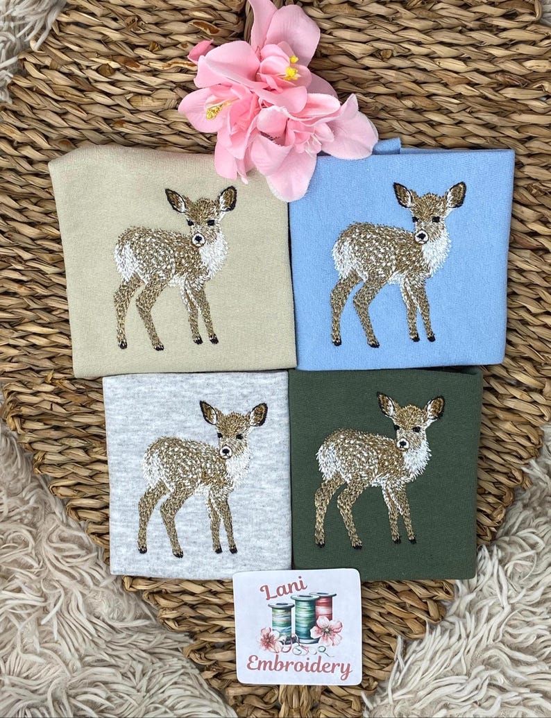 May include: Four embroidered deer designs on different colored squares: beige, light blue, gray, and dark green. A small square with the text "Lani Embroidery" and images of spools of thread is at the bottom. A pink flower is at the top.
