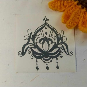 May include: Black and white mandala design with a floral motif. The design is intricate and detailed, with a central flower surrounded by swirling patterns.